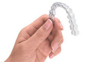 A woman's hand holding an Invisalign aligner