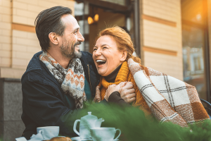 A smiling middle aged man and woman, laughing and enjoying brunch outside