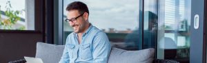 Man smiling while sitting outside on his laptop