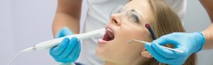 woman receiving dental care with a handheld UV light